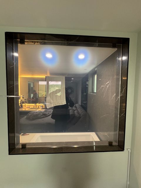 Properly installed switchable smart film on a residential bathroom partition demonstrating clean frosted-mode activation