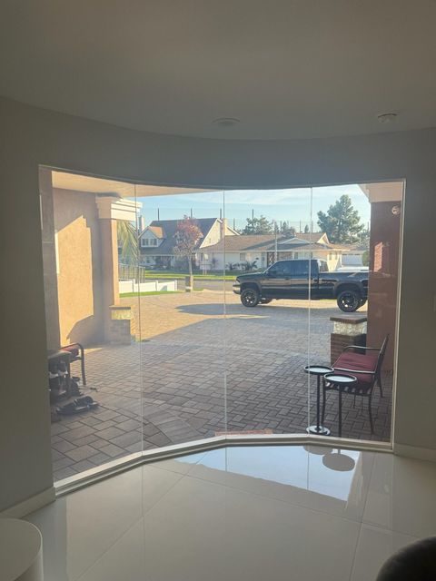 Luxury smart glass for homes — clear-mode curved floor-to-ceiling smart glass wall in a high-end Beverly Hills residential space designed for luxury privacy spec