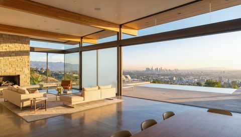 Los Angeles hillside home with a floor-to-ceiling clear switchable smart glass wall overlooking the LA basin — several glass panels switched to frosted privacy mode