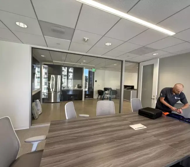 Technician preparing to apply switchable film to a modern LA conference-room glass wall